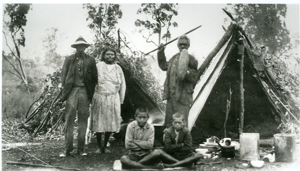 group-outside-gunyas-at-cherbourg-aboriginal-settlement_1930s