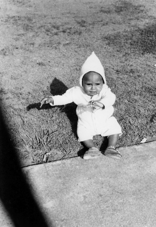 Baby sitting on lawn at Cherbourg Hospital c1962
