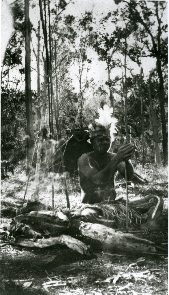 Decorated man with fire sticks at Barambah Aboriginal Settlement c1920